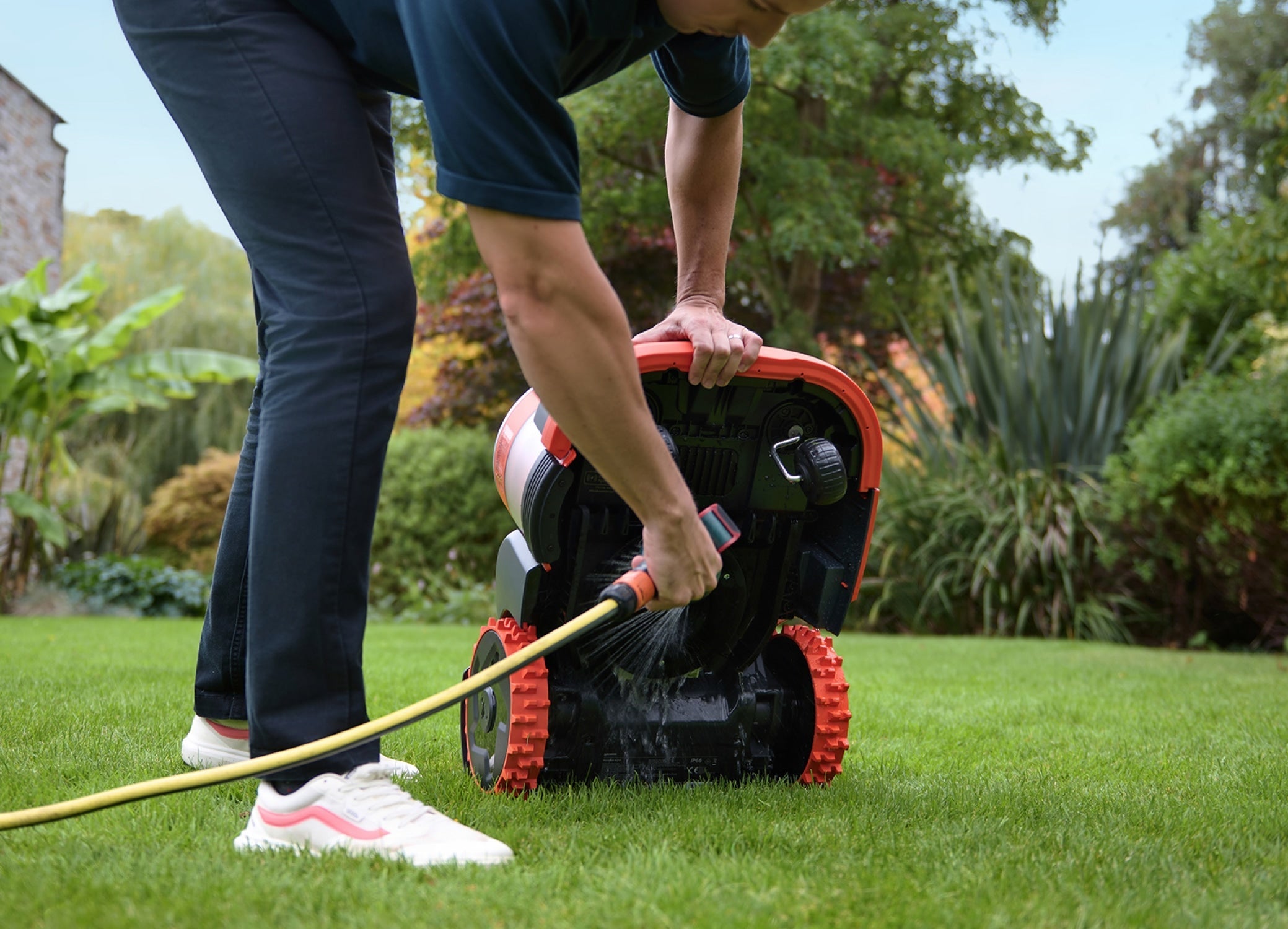 A Navimow i105E robot lawn mower is being cleaned outside.