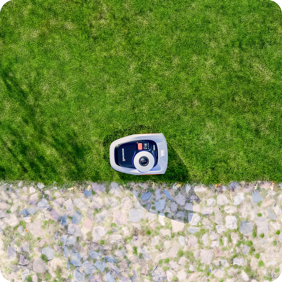 Navimow i110N robot lawn mower on green grass near stones.