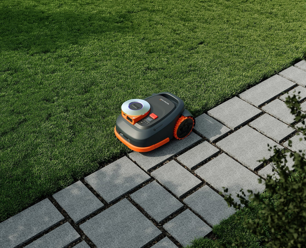 Segway Navimow robot lawn mower on green grass beside stones.