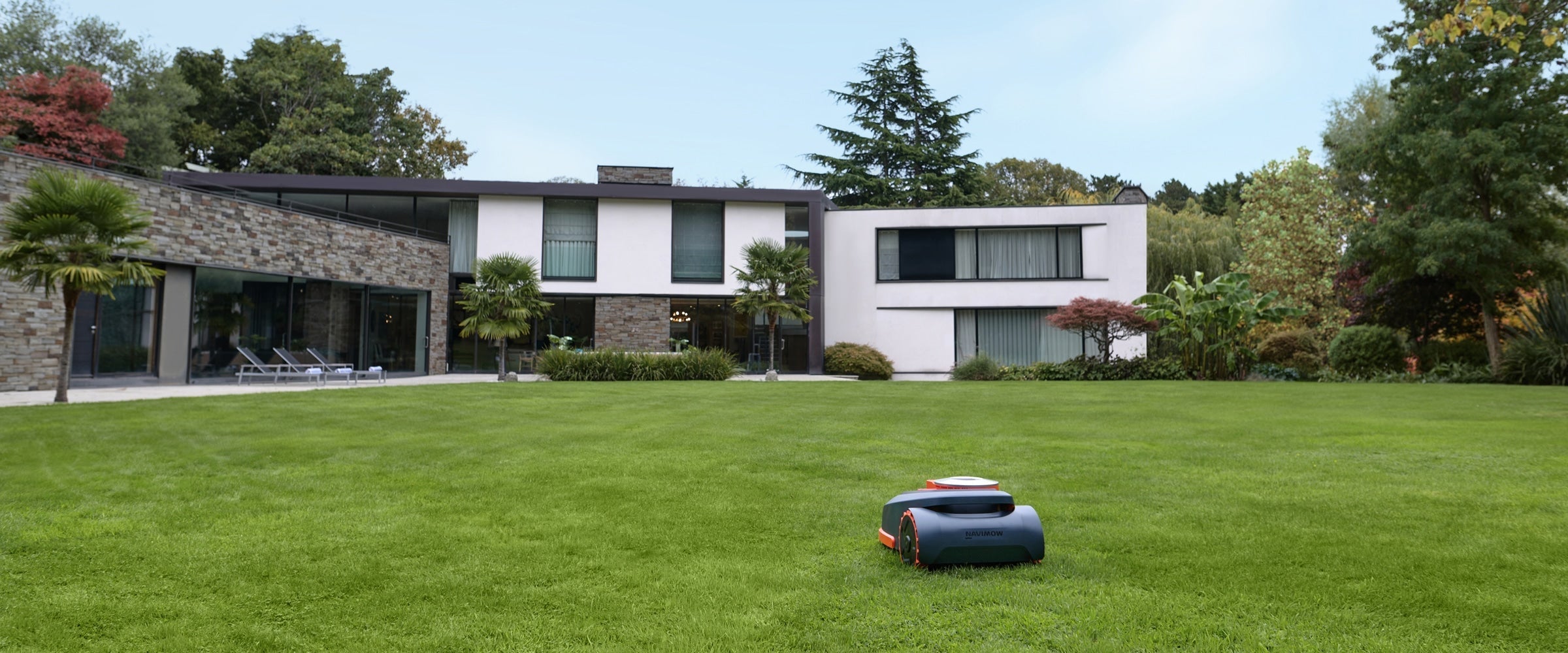 Navimow i110E robot lawn mower mows the green backyard grass.