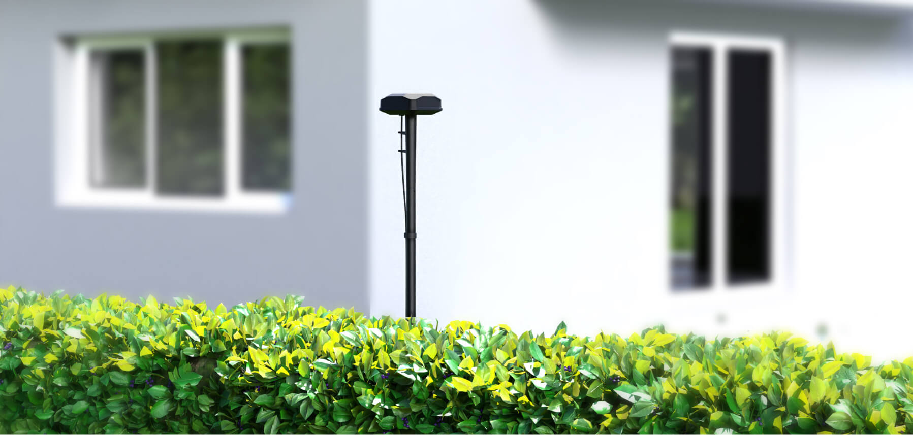 Navimow i105E robot lawn mower antenna stands behind green hedges.