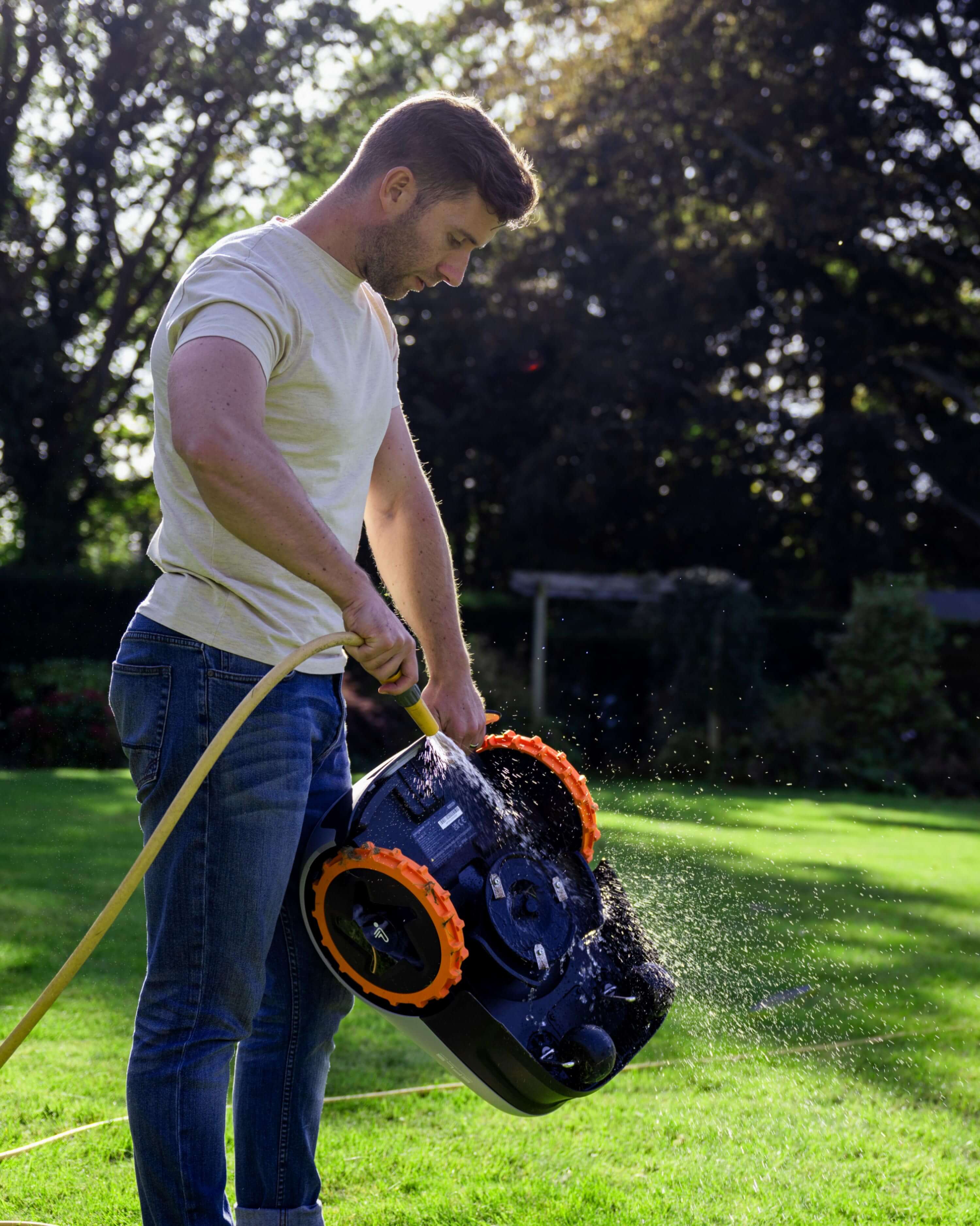 The man is washing a Navimow i105E robot lawn mower.