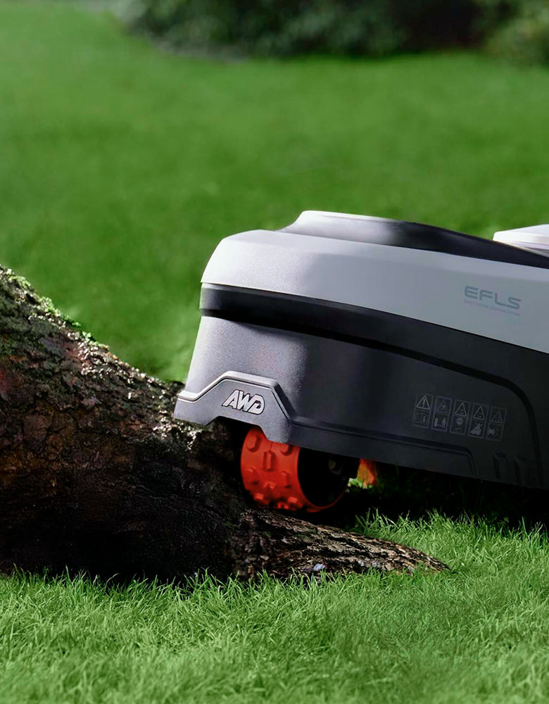 Navimow i110E robot lawn mower mows grass near a tree.